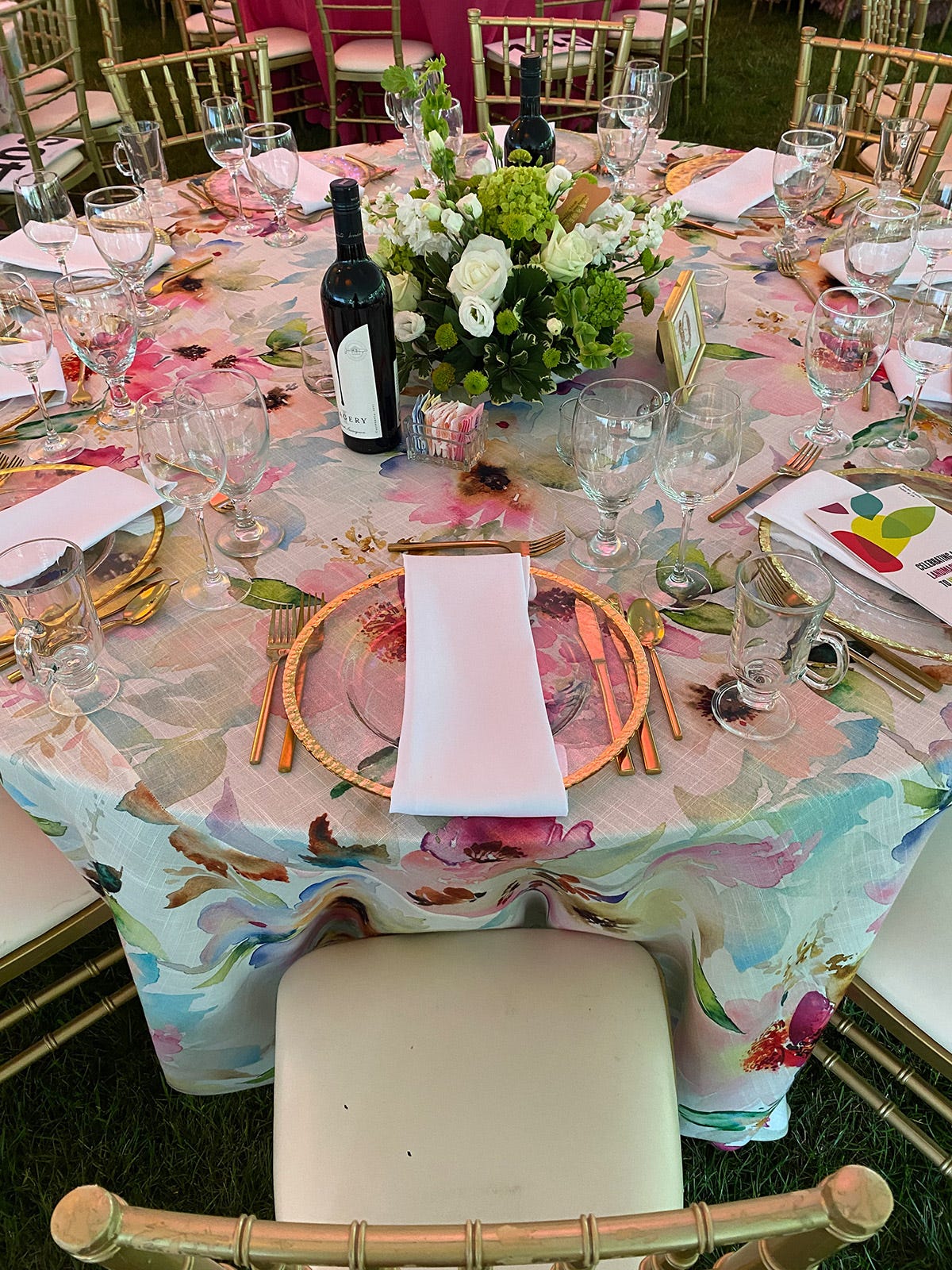 corporate appreciation event table with floral linens and gold chairs